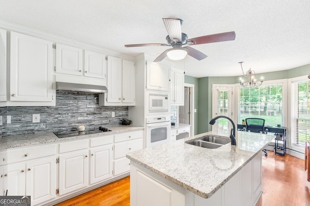 kitchen with pendant lighting, white cabinetry, an island with sink, sink, and white appliances