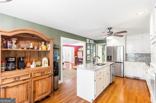 kitchen featuring sink, light hardwood / wood-style flooring, a kitchen island with sink, white cabinetry, and stainless steel appliances