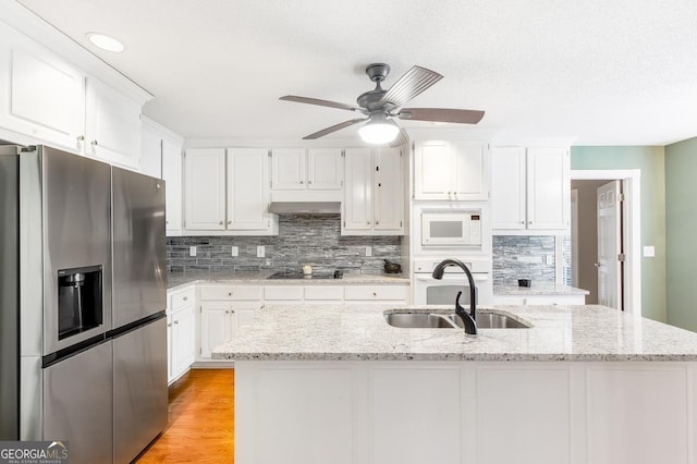 kitchen with white cabinetry, sink, light stone counters, and white appliances