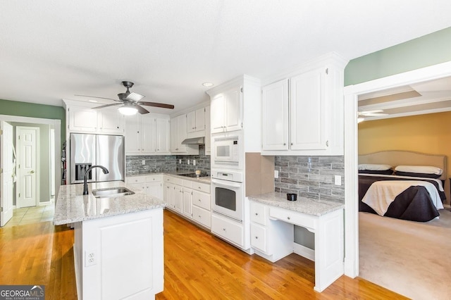 kitchen featuring white cabinetry, an island with sink, sink, and white appliances