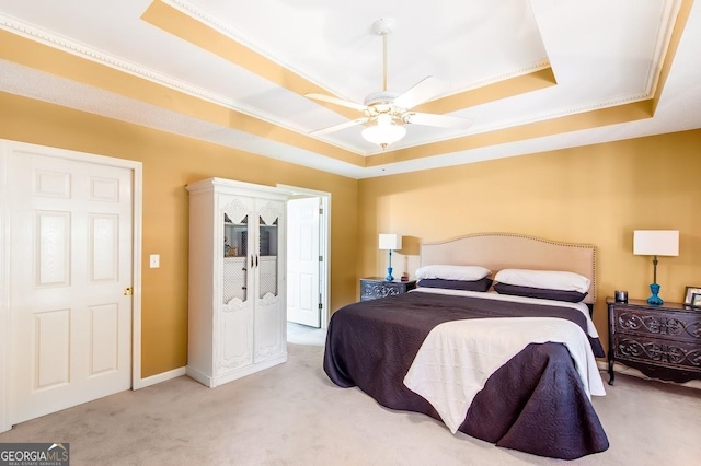 carpeted bedroom with ornamental molding, ceiling fan, and a tray ceiling