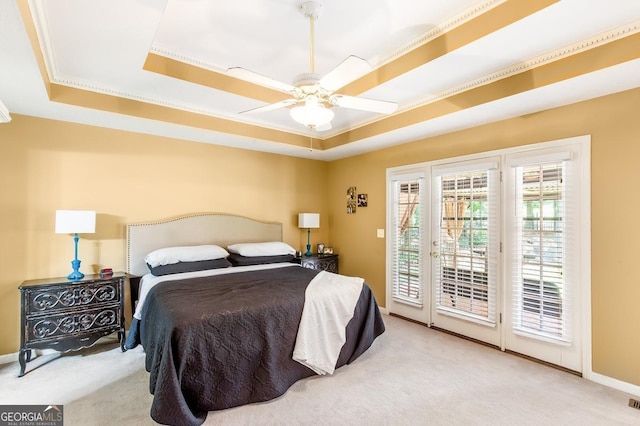 bedroom with light carpet, access to outside, ceiling fan, and a tray ceiling