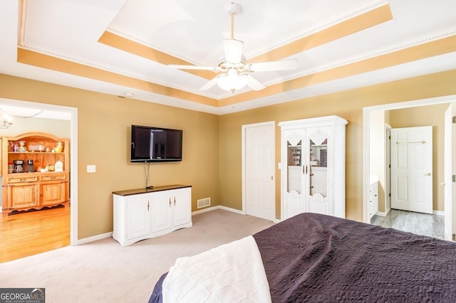 carpeted bedroom with crown molding, ceiling fan, and a tray ceiling