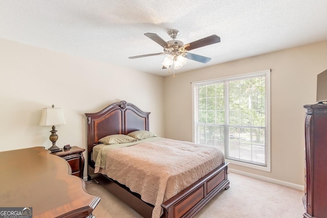 bedroom with ceiling fan, light carpet, and a textured ceiling