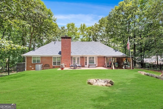 back of house with central AC, an outdoor fire pit, a patio area, and a lawn