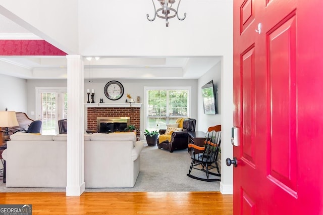 living room with a fireplace, a tray ceiling, a wealth of natural light, and hardwood / wood-style flooring