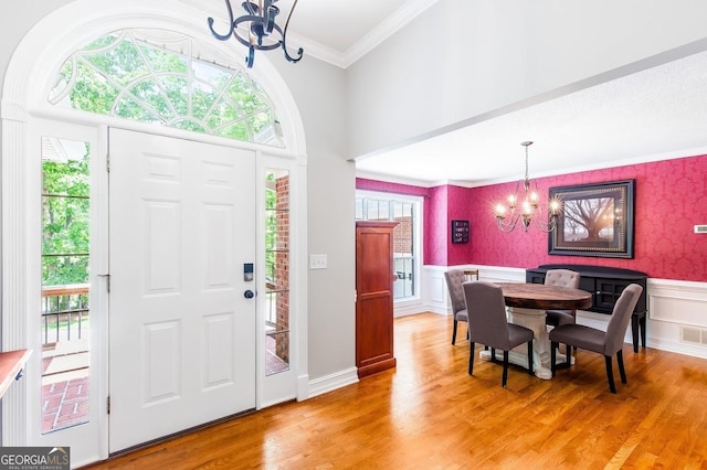 entryway featuring wood-type flooring, ornamental molding, and a chandelier