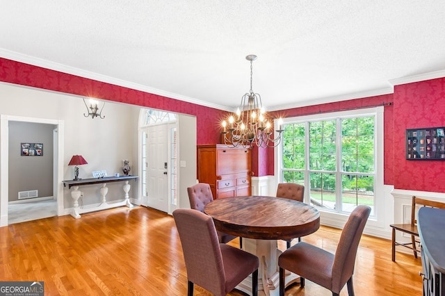 dining room with crown molding, a wealth of natural light, a chandelier, and light hardwood / wood-style flooring