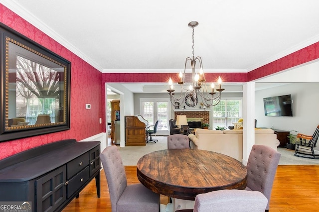 dining area with crown molding, a brick fireplace, and plenty of natural light