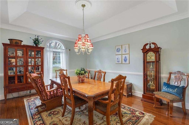 dining room with crown molding, dark hardwood / wood-style floors, a raised ceiling, and a chandelier