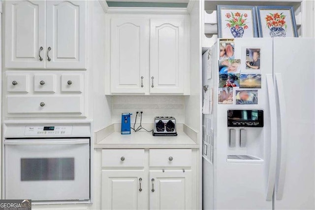 kitchen featuring white appliances, decorative backsplash, and white cabinets