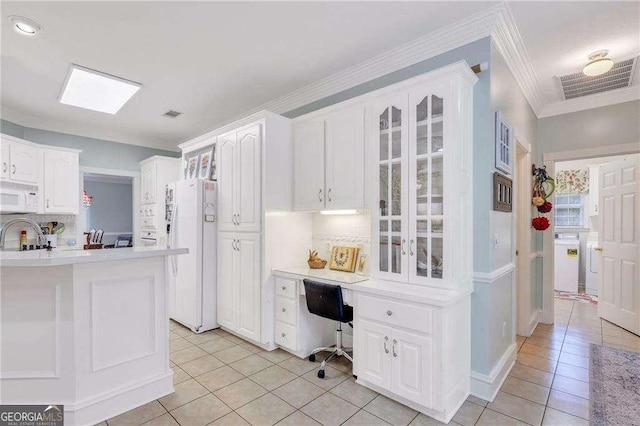 kitchen with light tile patterned flooring, white cabinetry, ornamental molding, white appliances, and backsplash