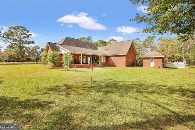 back of property with an outdoor structure, central air condition unit, and a lawn