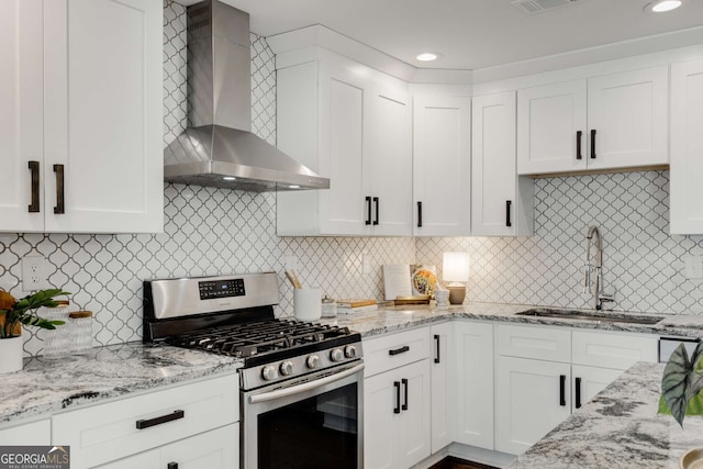 kitchen featuring tasteful backsplash, sink, white cabinets, gas range, and wall chimney exhaust hood