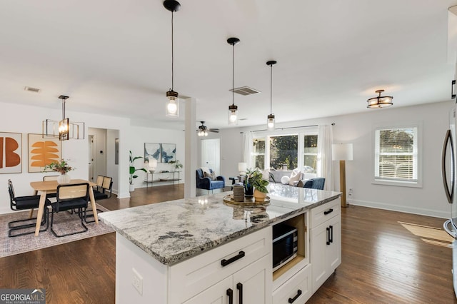 kitchen with a kitchen island, pendant lighting, white cabinets, dark hardwood / wood-style flooring, and light stone countertops