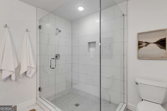 bathroom featuring a shower with door and toilet