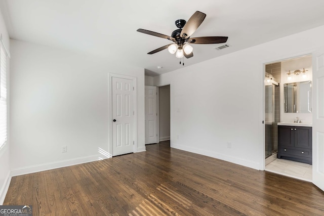 unfurnished bedroom with ensuite bathroom, multiple windows, wood-type flooring, sink, and ceiling fan