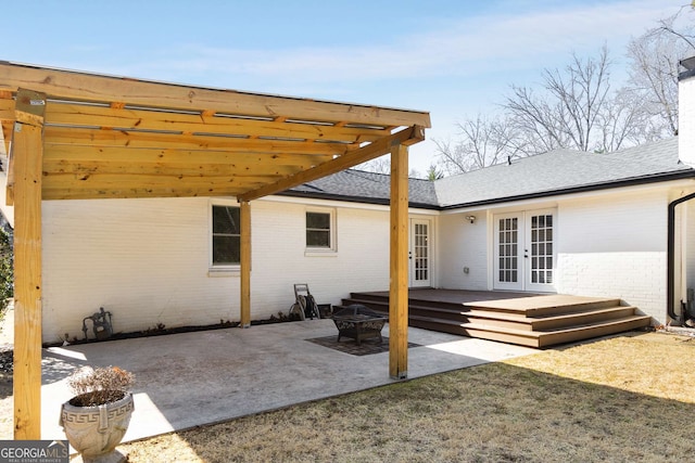 rear view of house with french doors, an outdoor fire pit, a wooden deck, and a patio area