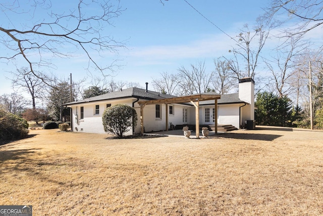 back of house with central AC unit, a patio area, and a lawn