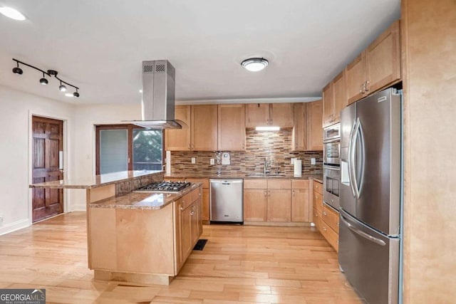 kitchen featuring sink, appliances with stainless steel finishes, a center island, light hardwood / wood-style floors, and island exhaust hood