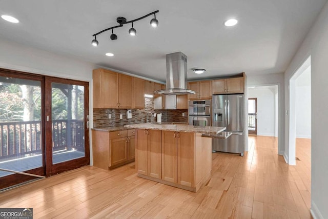 kitchen featuring appliances with stainless steel finishes, backsplash, island range hood, light stone countertops, and a kitchen island