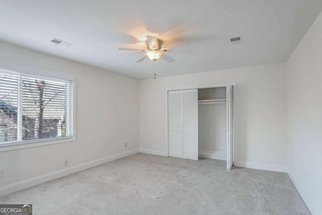 unfurnished bedroom featuring ceiling fan, a closet, and light carpet