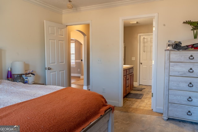 bedroom with baseboards, arched walkways, light colored carpet, ensuite bathroom, and crown molding