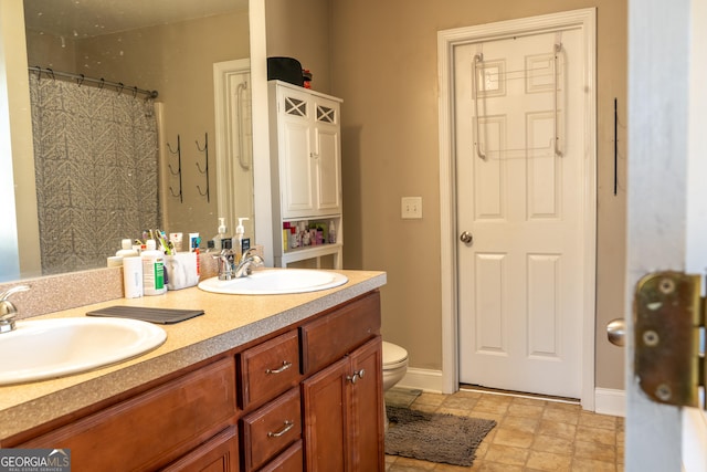 full bathroom featuring baseboards, a sink, toilet, and double vanity