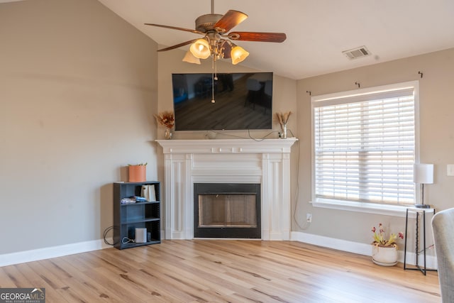 unfurnished living room with lofted ceiling, a fireplace, wood finished floors, visible vents, and baseboards