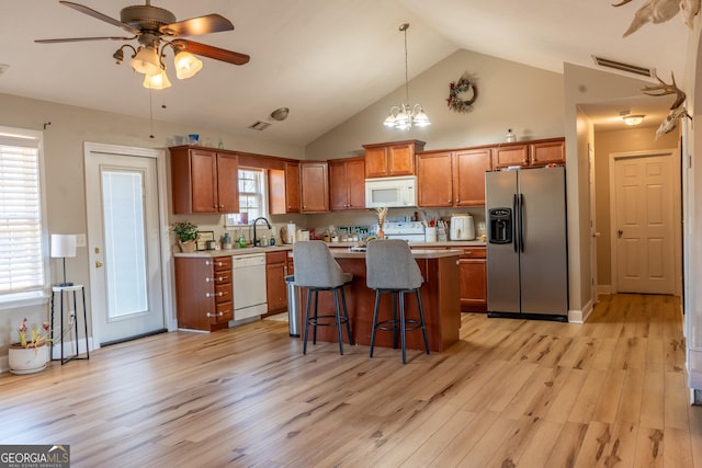 kitchen with white appliances, visible vents, brown cabinets, light countertops, and a sink