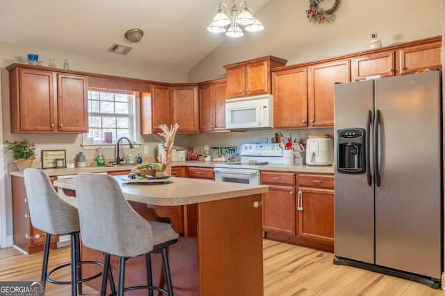 kitchen with white appliances, a sink, visible vents, light countertops, and light wood-type flooring