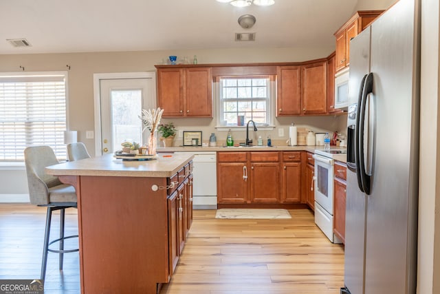 kitchen with light countertops, white appliances, a sink, and visible vents