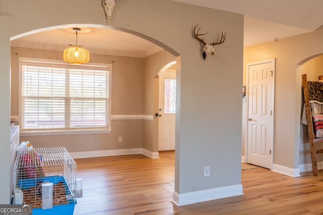 unfurnished room with arched walkways, crown molding, baseboards, and wood finished floors