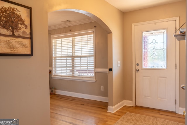 foyer entrance featuring baseboards, visible vents, arched walkways, and wood finished floors