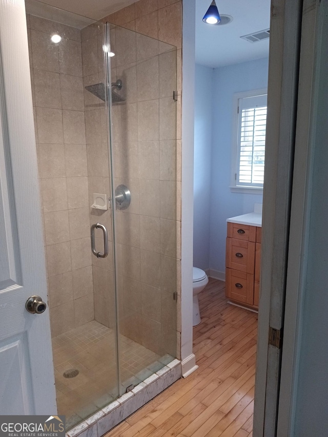 bathroom featuring hardwood / wood-style flooring, vanity, toilet, and a shower with shower door