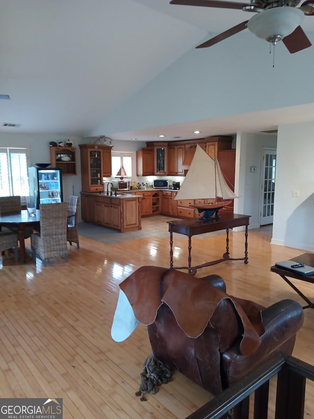 interior space featuring ceiling fan, high vaulted ceiling, sink, and light hardwood / wood-style floors