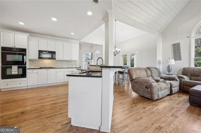 kitchen featuring sink, black appliances, kitchen peninsula, decorative backsplash, and white cabinets