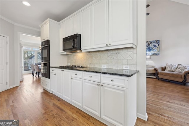 kitchen with white cabinets, backsplash, black appliances, crown molding, and light wood-type flooring