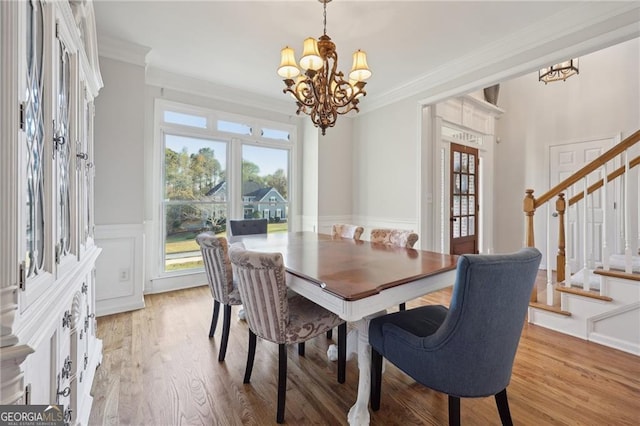 dining space with crown molding, a chandelier, and light wood-type flooring