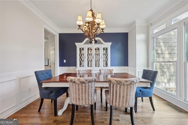 dining space with crown molding, a chandelier, and light hardwood / wood-style flooring