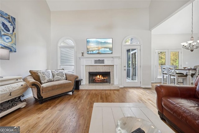 living room featuring a towering ceiling, an inviting chandelier, and light hardwood / wood-style floors