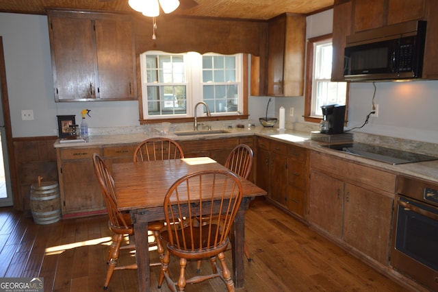 kitchen featuring appliances with stainless steel finishes, sink, dark wood-type flooring, and wood walls