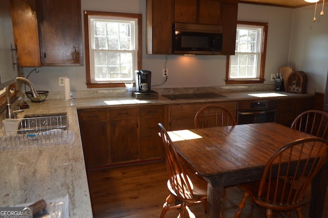 kitchen featuring light stone counters, sink, dark wood-type flooring, and black appliances