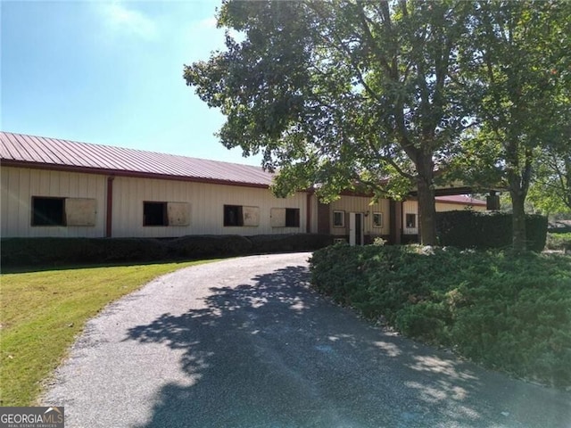 single story home featuring metal roof, a front lawn, and driveway