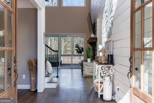 interior space featuring a wealth of natural light, dark wood-style flooring, baseboards, and a high ceiling