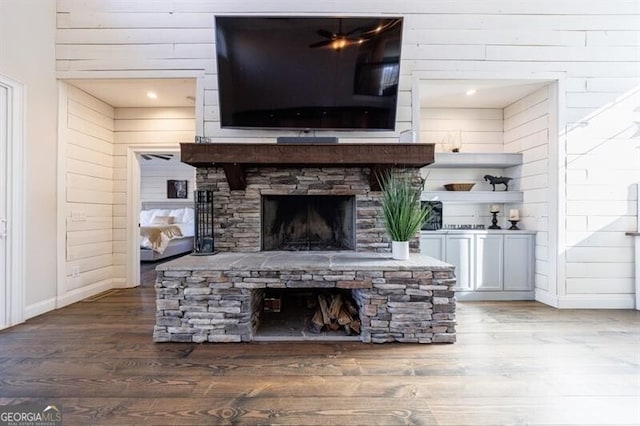 living area with a fireplace, wooden walls, baseboards, and wood finished floors