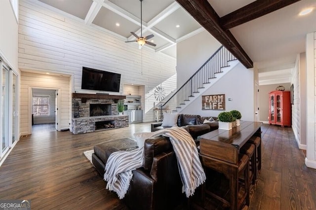 living area with a high ceiling, a fireplace, dark wood finished floors, and beam ceiling