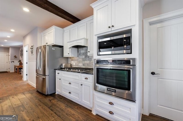 kitchen with under cabinet range hood, appliances with stainless steel finishes, white cabinets, and dark wood-type flooring