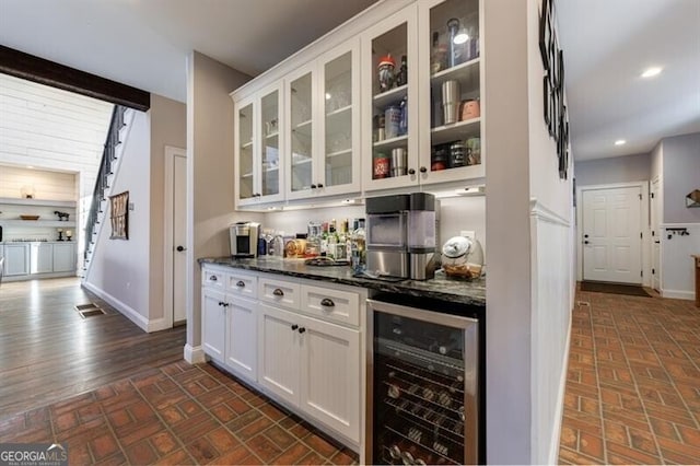 bar with brick floor, wine cooler, a bar, and baseboards