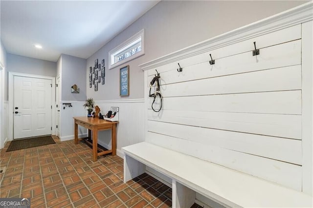 mudroom with brick floor, recessed lighting, and wainscoting